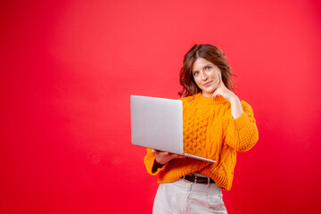 young woman on a red background holds a laptop