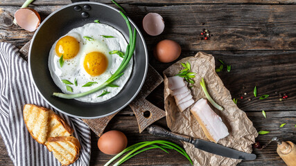 tasty fried eggs and lard bacon on wooden table. Ukrainian or belorussian cuisine. banner, catering menu recipe place for text, top view
