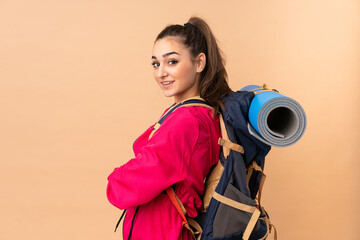 Obraz premium Young mountaineer girl with a big backpacker isolated on beige background laughing