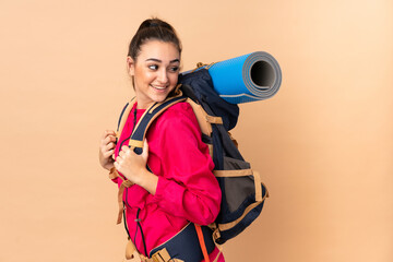 Young mountaineer girl with a big backpacker isolated on beige background