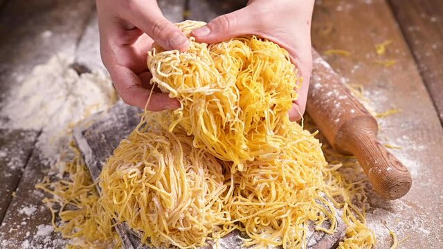 Tagliatelle pasta is thin. Traditional Italian named Angel Hair (capellini d'angels). Woman cooking Italian egg pasta, homemade and fresh in flour on a cutting table. vertical video for social media