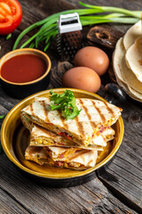 Mexican food cuisine traditional dish quesadilla ith scramble eggs, vegetables, ham and cheese. vertical image