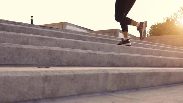Asian buxom woman running up city stairs jogging and running in urban training workout. Slow motion.
