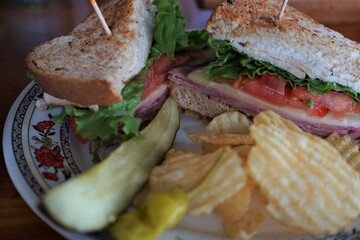 Delicious BLT sandwich made of wheat bread, cheese, ham and lettuce with potato chips and pickles on plate - BLT サンドウィッチ ピクルス ポテトチップス