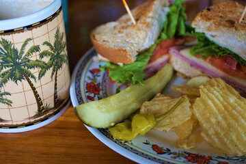 Delicious BLT sandwich made of wheat bread, cheese, ham, tomato and lettuce with potato chips and pickles on plate - BLT サンドウィッチ ピクルス ポテトチップス