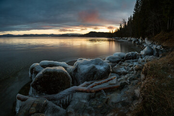 Icy frozen shore of the lake in sunset time.