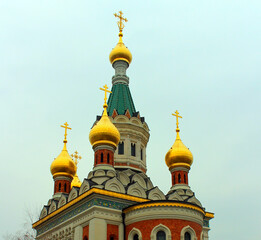 Fototapeta na wymiar Orthodox Christian Church of St. Nicholas in Vienna. A building with domes and crosses on them.