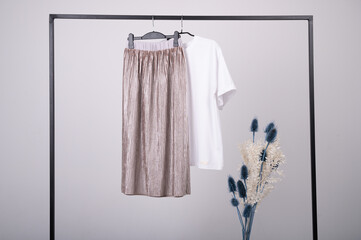 Capsule spring wardrobe concept. T-shirt and skirt in pastel colors handing on a rack.