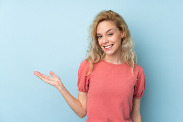 Fototapeta premium Young blonde woman isolated on blue background holding copyspace imaginary on the palm