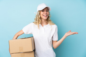 Young delivery woman isolated on blue background holding copyspace imaginary on the palm