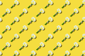 Creative pattern with narcissus flowers on yellow background, copy space. Spring concept. Greeting card. Mothers Day, Valentines Day, wedding, birthday. Flat lay, top view