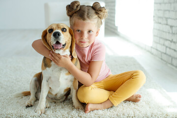 Child with a dog. Little girl plays with a dog at home. Child and animal. High quality photo.