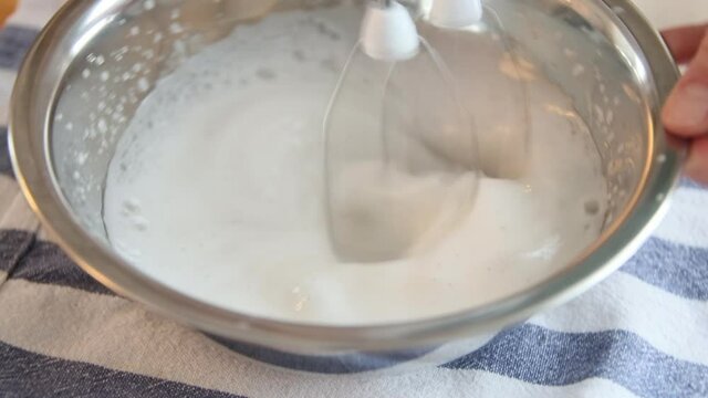 The whipping cream for a vegan cake Esterhazy. Whipping eggs with a mixer close-up. 60 fps.
