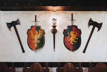 Shields, swords, axes and a torch-shaped wall lamp. Medieval concept and knightly elements....