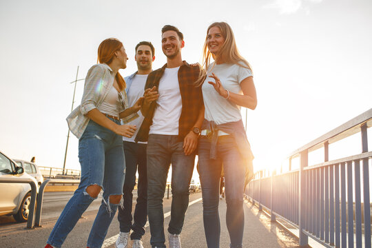 Group Of Friends Hangout At The City Street.They Walking Over The Bridge And Joying In Sunset.	
