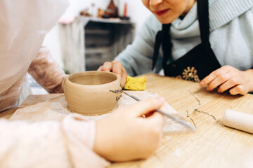 Mother and daughter decorate a clay plate before firing in a pottery studio, decorate a plate with lavender branches