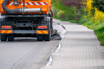 Sweeper is cleaning empty road.