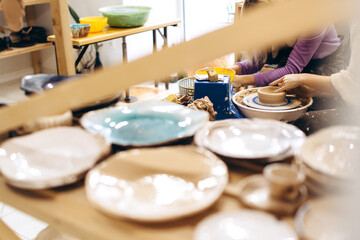 Creative process of creating pottery by mother and daughters. Female hands in a pottery workshop.