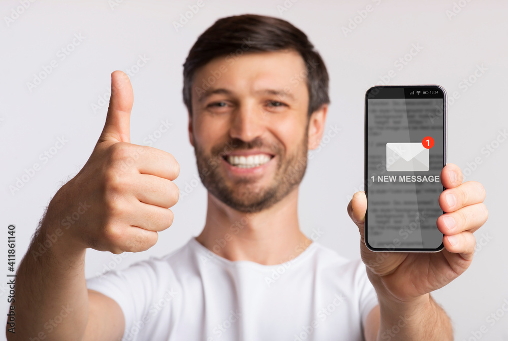 Poster Man Showing Smartphone With New Message Gesturing Thumbs-Up, Gray Background