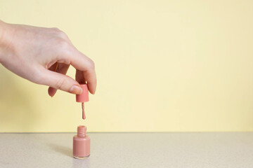 female hand holds a brush from manicure varnish over a jar Concept of topical shades for manicure
