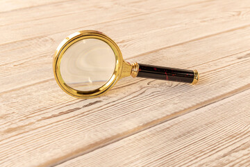 A magnifying glass on a wooden table. The concept of information search. Selective focus.