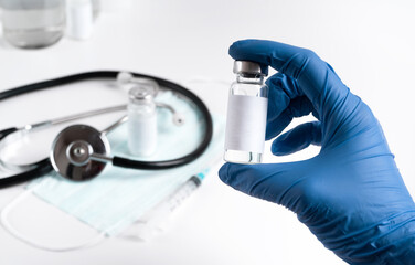 Fototapeta premium healthcare professional in a blue disposable glove shows a vaccine bottle before vaccination. Healthcare concept