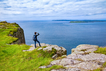 Obraz premium tourist with backpack standing on the cliff Fair Head, Northern Ireland, UK