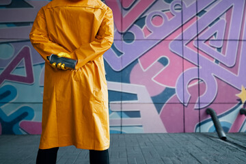 Cropped image of street artist with spray paint can in hand standing near the wall