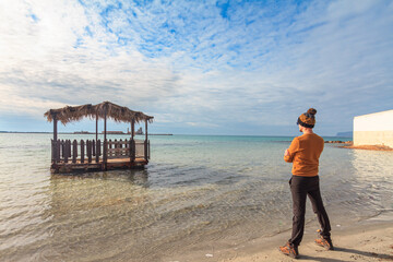 Rear view of a caucasian man standing on a sand shore with arms crossed