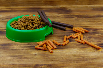 Dog delicacy food and feed in green plastic bowl on wooden background. Dog care concept