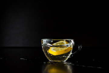 water splashes. freezing motion. frozen alcohol spray. a slice of lemon fell into a cup of water. stopped action. menu design. side view. advertising poster