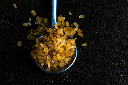 Close-up of a spoonful of brown cane sugar on a table