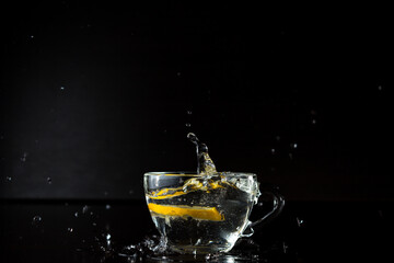 water splashes. freezing motion. frozen alcohol spray. a slice of lemon fell into a cup of water. stopped action. menu design. side view. advertising poster
