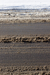 Dirty car road with melted black and brown snow, wet spring