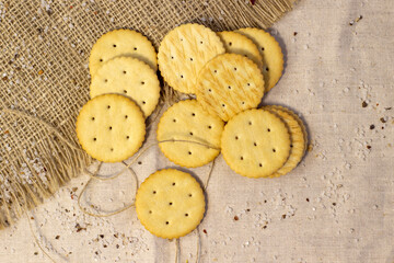 Salty biscuit cracker on coarse linen cloth close up Narrow focus line, shallow depth of field