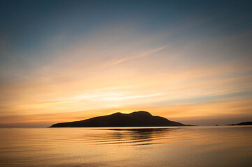 Fototapeta na wymiar Sunrise over Holy Island from Lamlash beach on the Isle of Arran