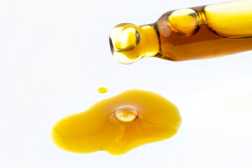 A macro shot of a glass pipette and a drop of CBD oil from cannabis extract, isolated on white.