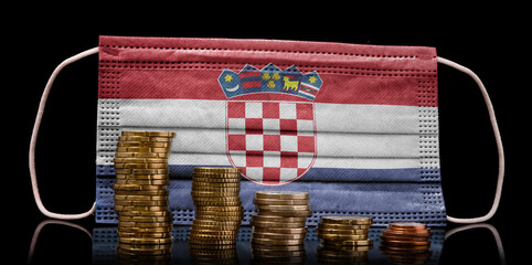 Medical mask with the flag of Croatia behind some shrinking stacks of various coins.(series)