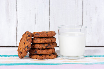 Delicious homemade cookies with chocolate and a glass cup of milk on a wooden table. Beautiful still life