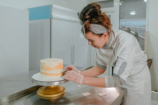 Female confectioner decorating birthday cake at confectionery studio