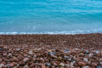 Multicolored round pebbles on the beach and blue sea