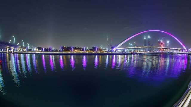 Illuminated Pedestrian Bridge over the Dubai Water Canal day to night transition timelapse which links Dubai Creek to Jumeirah Beach weaving through Deira, Downtown Dubai and Safa Park. Skyscrapers