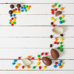 Easter chocolate eggs and candies on white wooden background