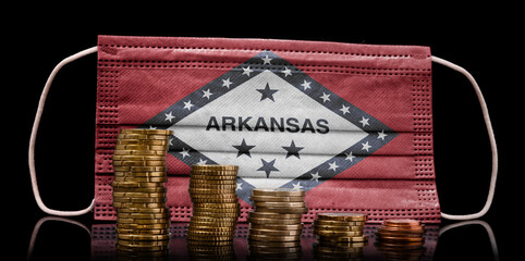 Medical mask with the flag of Arkansas behind some shrinking stacks of various coins.(series)