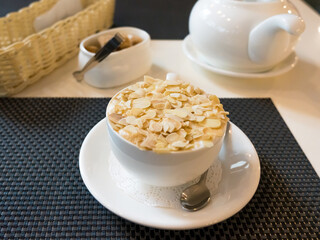 Cup of coffee sprinkled with almonds on the table for breakfast