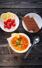 Thai national soup Tom yam with shrimps, lemon, cherry tomatoes and slices on a wooden table, flatly
