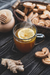 hot drink tea with lemon, honey and ginger with gingerbread cookies on wooden background