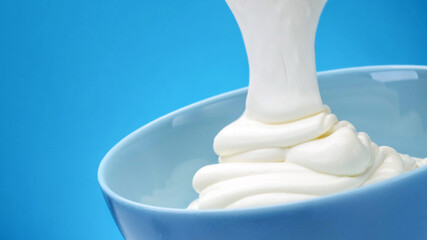 Flowing fresh greek yogurt on blue background