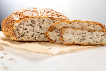 Sliced bread on baking paper with flax and sunflower seeds. Fresh, tasty round wheat bread with flax seeds.