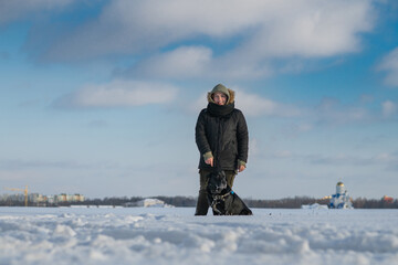 Fototapeta na wymiar Young handsome girl with a labrador retriever on a snowy field.